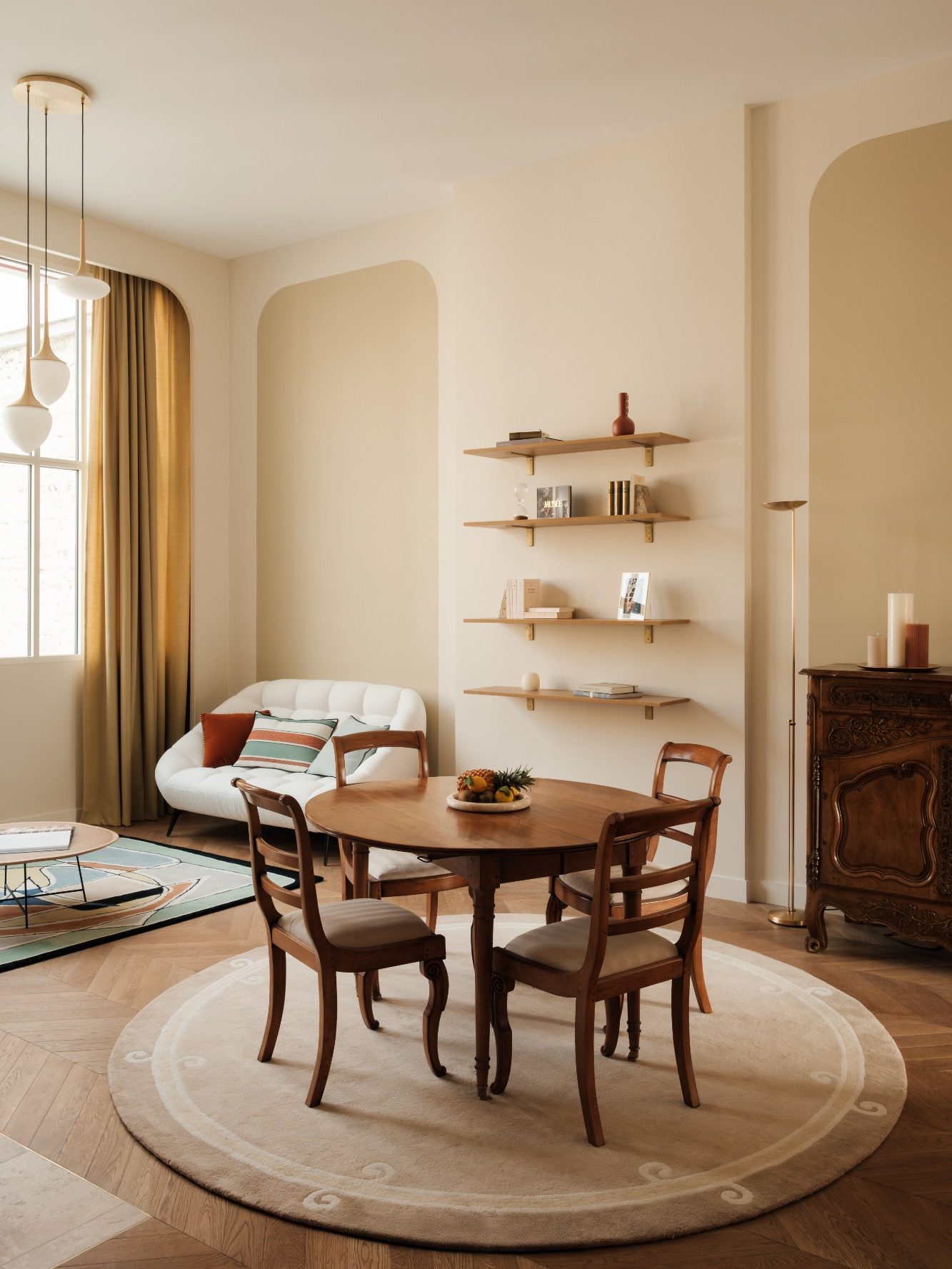 Salle à manger lumineuse avec une table en bois et des chaises, arches murales et décor minimaliste et accueillant.
