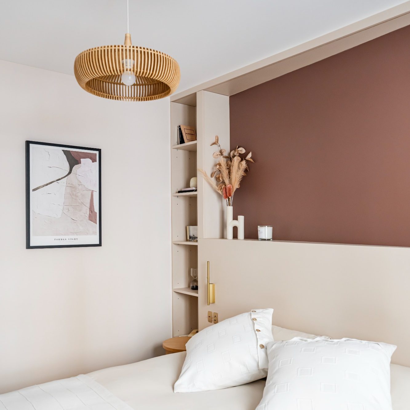 Chambre moderne avec lit, tête de lit, mur brun rosé, décoration florale et lampe en bois.