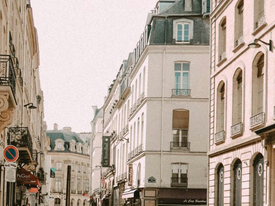 Rue animée avec façades historiques et bâtiment élégant à Paris.