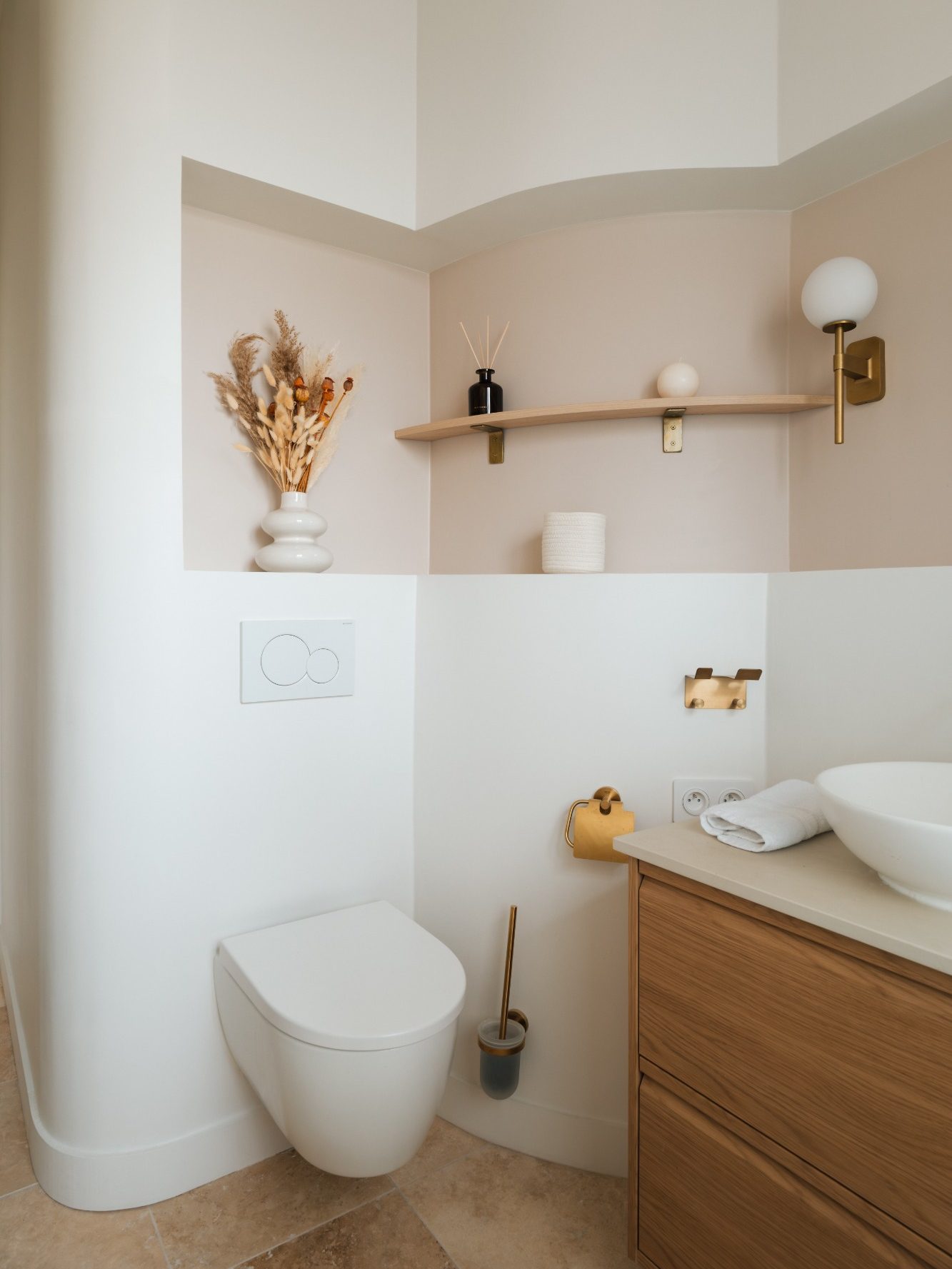 Toilettes modernes avec murs clairs, niche aménagée avec étagère en bois et décoration minimaliste.