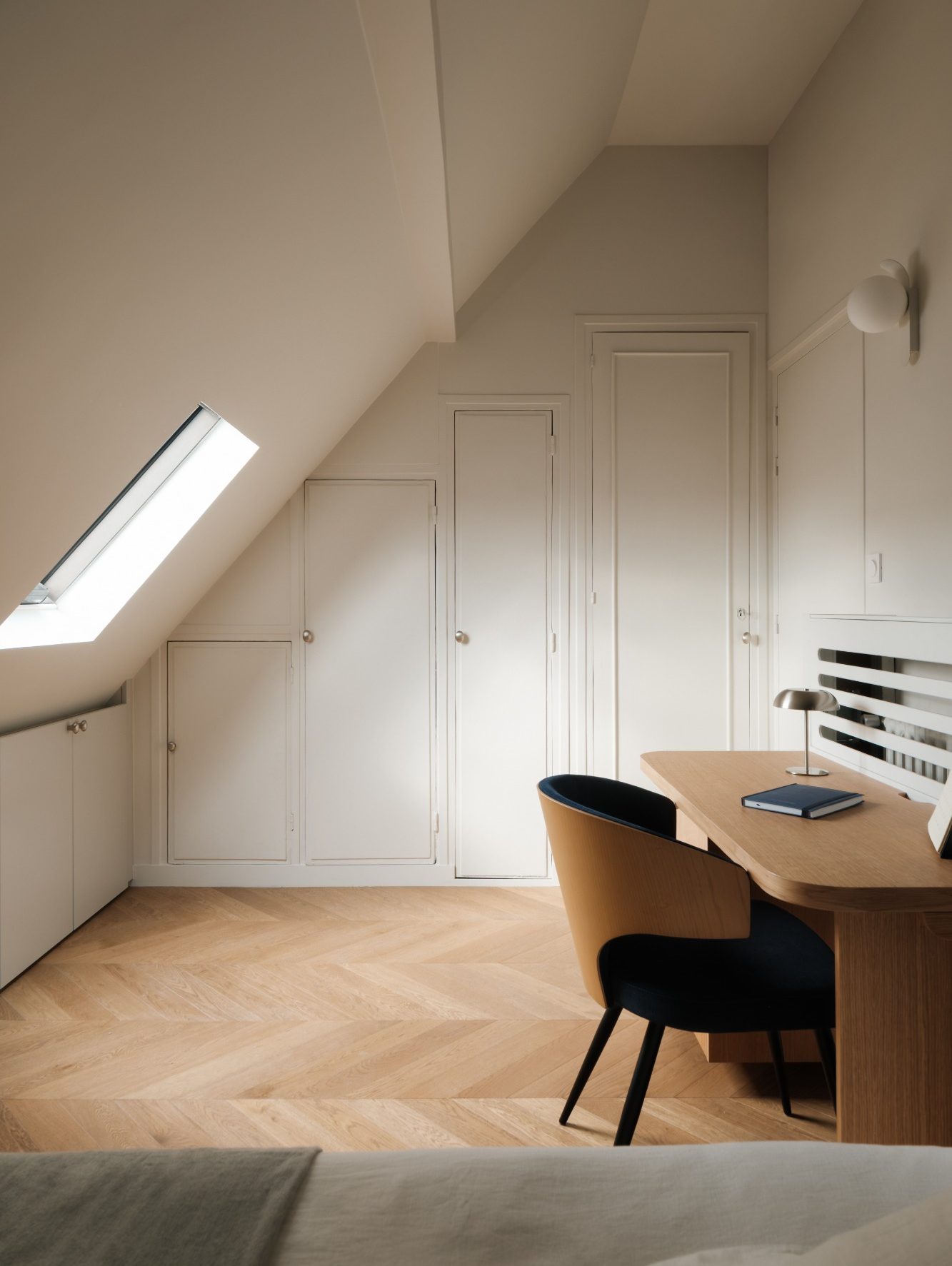 Une chambre en soupente optimisée avec de nombreux rangements, un bureau, une chaise et un lit