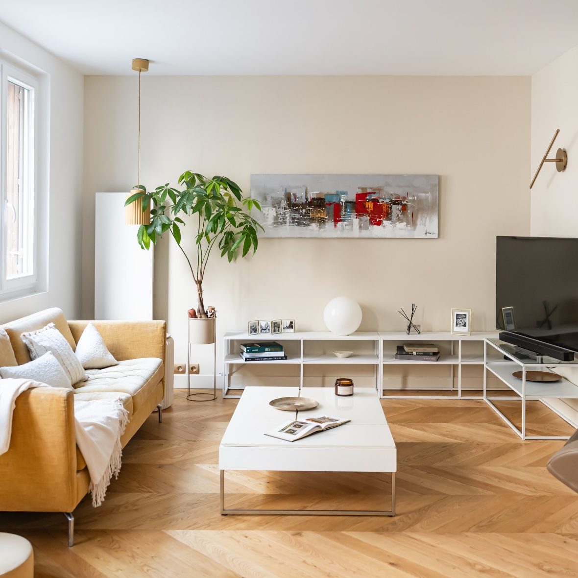 Salon lumineux avec canapé jaune moutarde, table basse blanche, meuble bas en enfilade.
