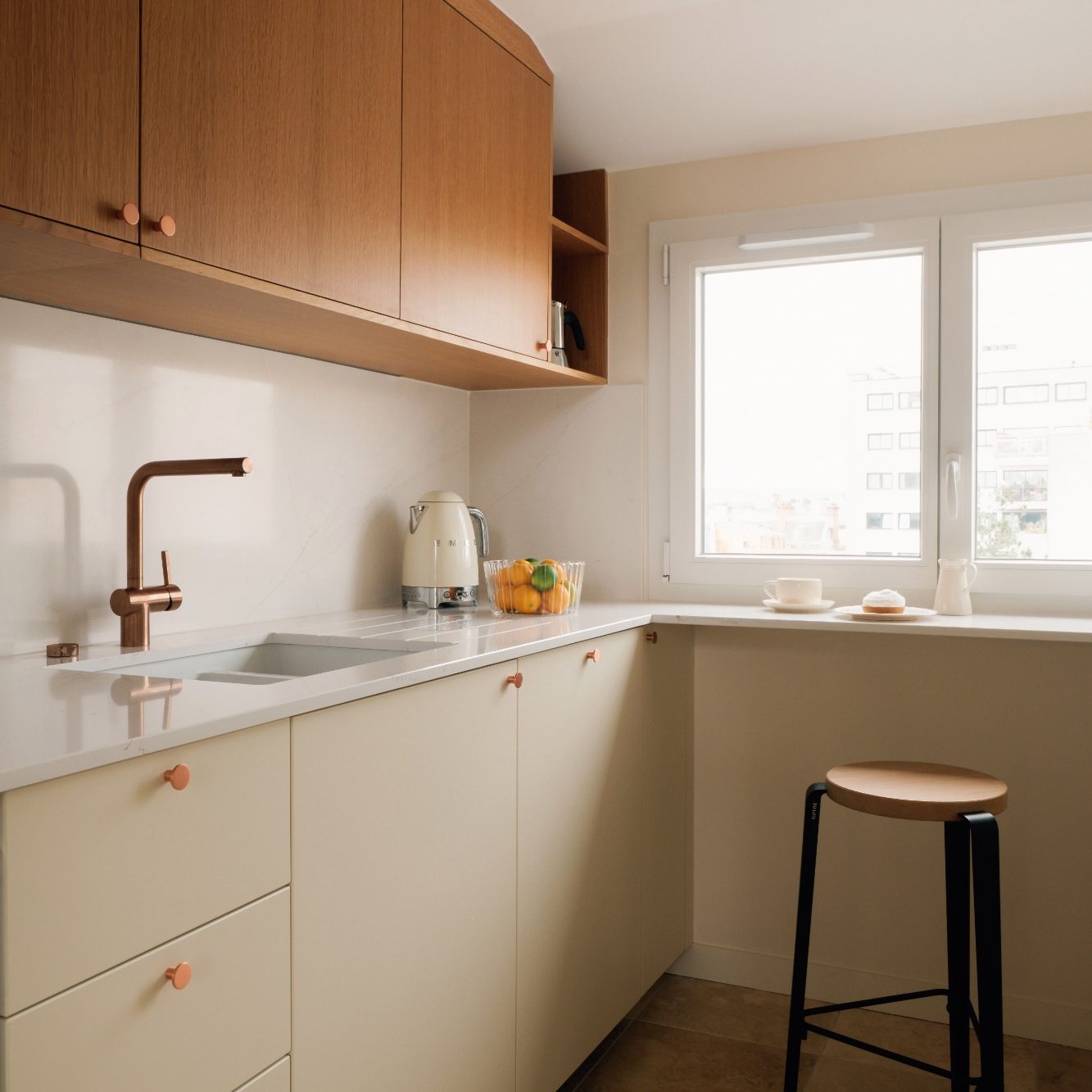 Cuisine moderne avec des meubles clairs et chêne, un évier et un tabouret sous un bar.