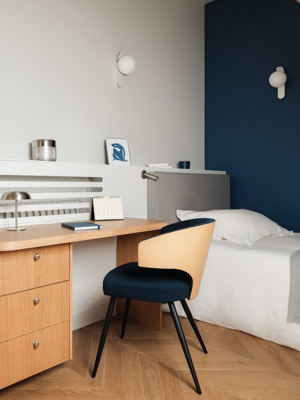 Chambre moderne avec un bureau en bois, une chaise, et un lit simple.