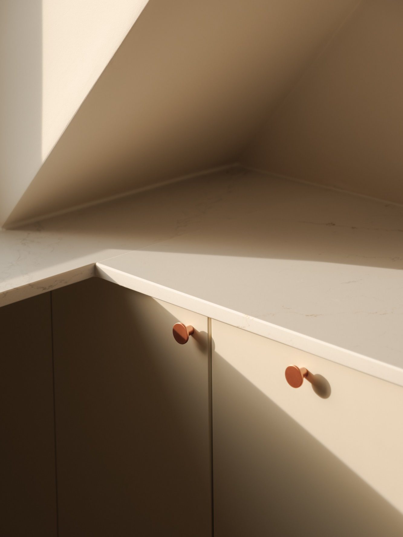 Coin d'un meuble aux teintes neutres, avec des poignées colorées. Lumière douce.