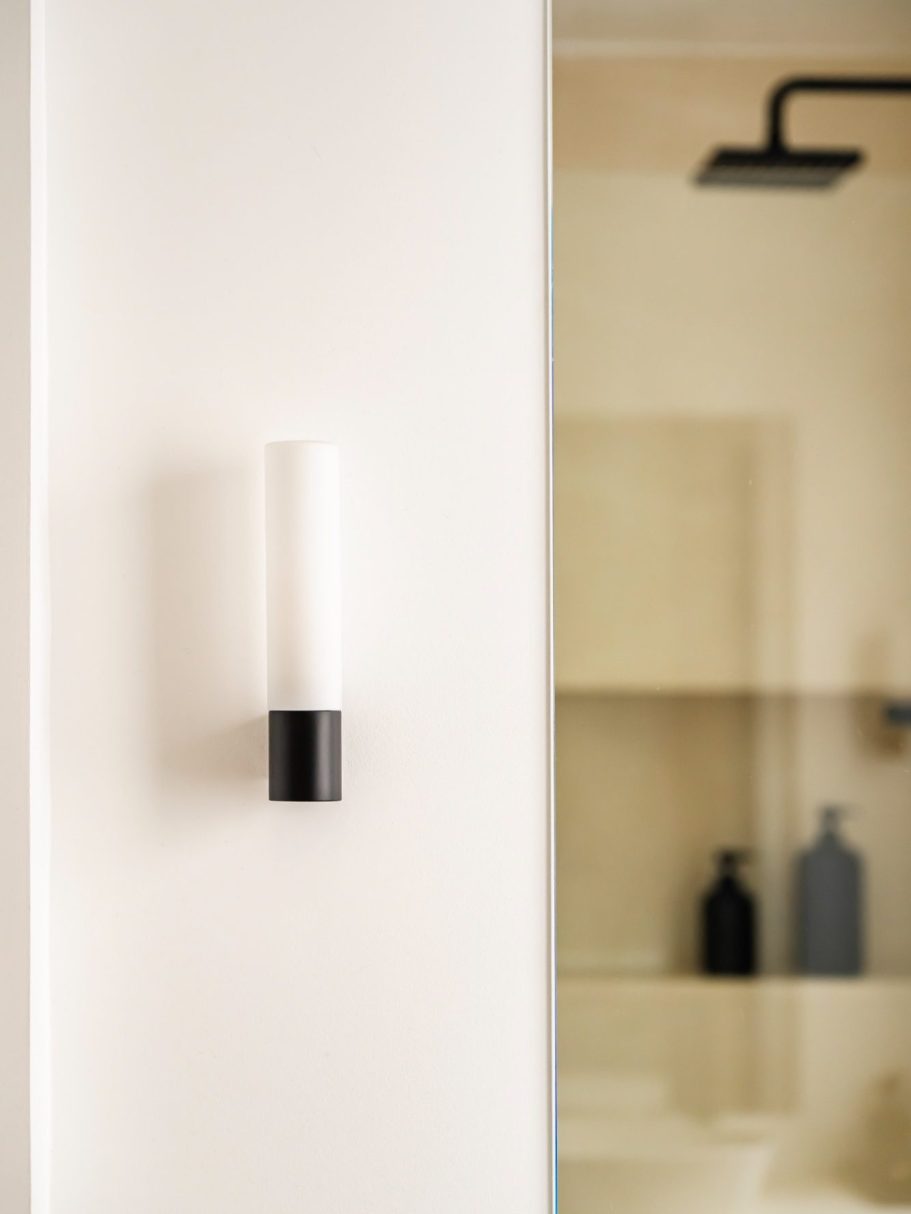 Applique murale moderne blanche et noire, avec douche dans le reflet du miroir.