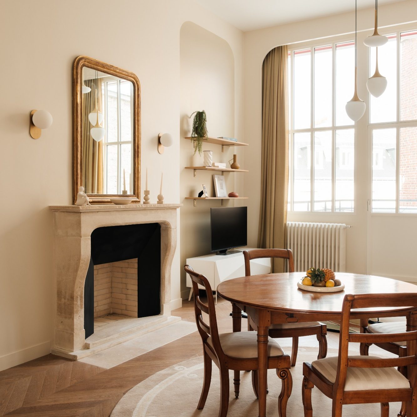 Intérieur d'un salon lumineux avec une table en bois et une cheminée en pierre.