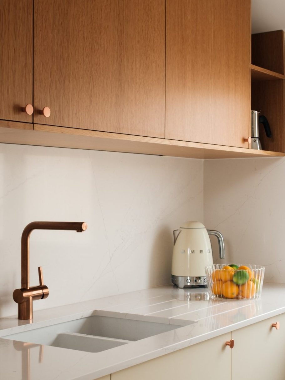 Évier moderne en marbre avec robinet en cuivre, fruits frais sur le comptoir.