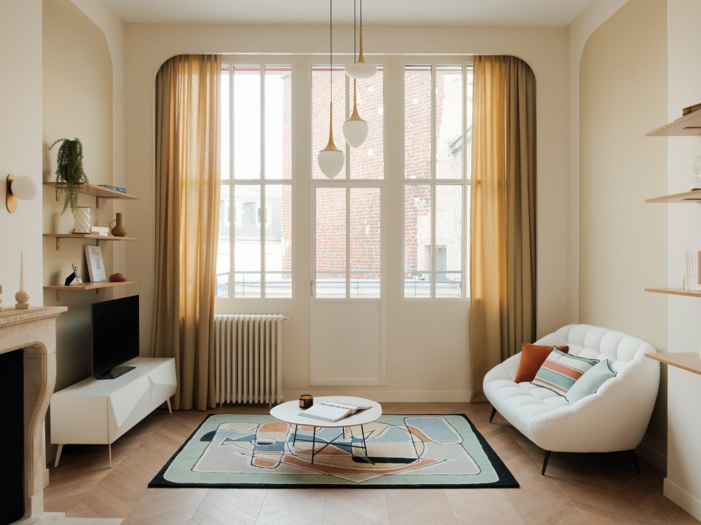 Salon lumineux avec canapé blanc, tapis coloré et grandes fenêtres aux rideaux jaunes.