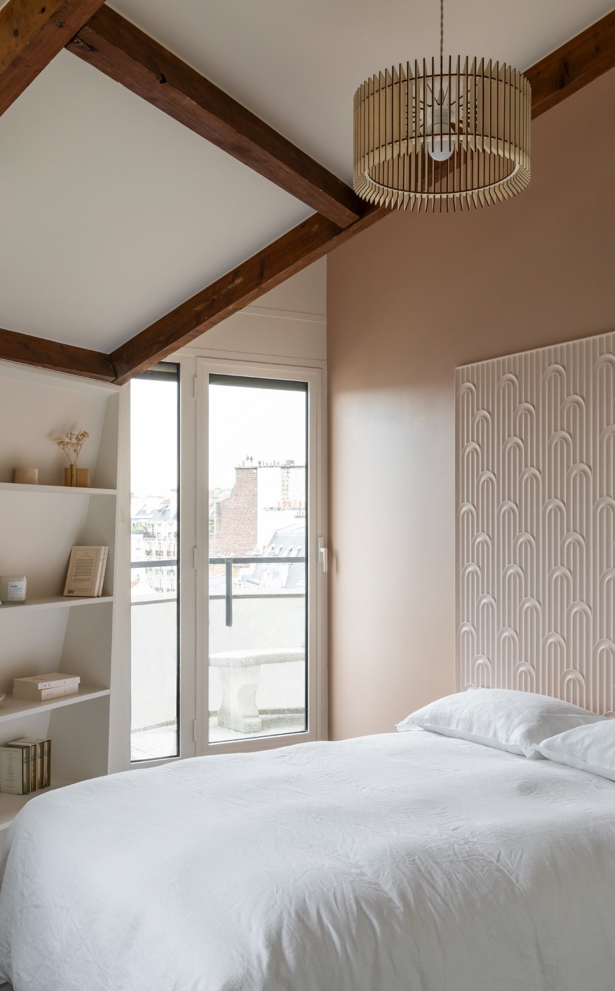 Chambre lumineuse avec un lit blanc, une tête de lit verticale en panneau 3D, une étagère et suspension en bois.